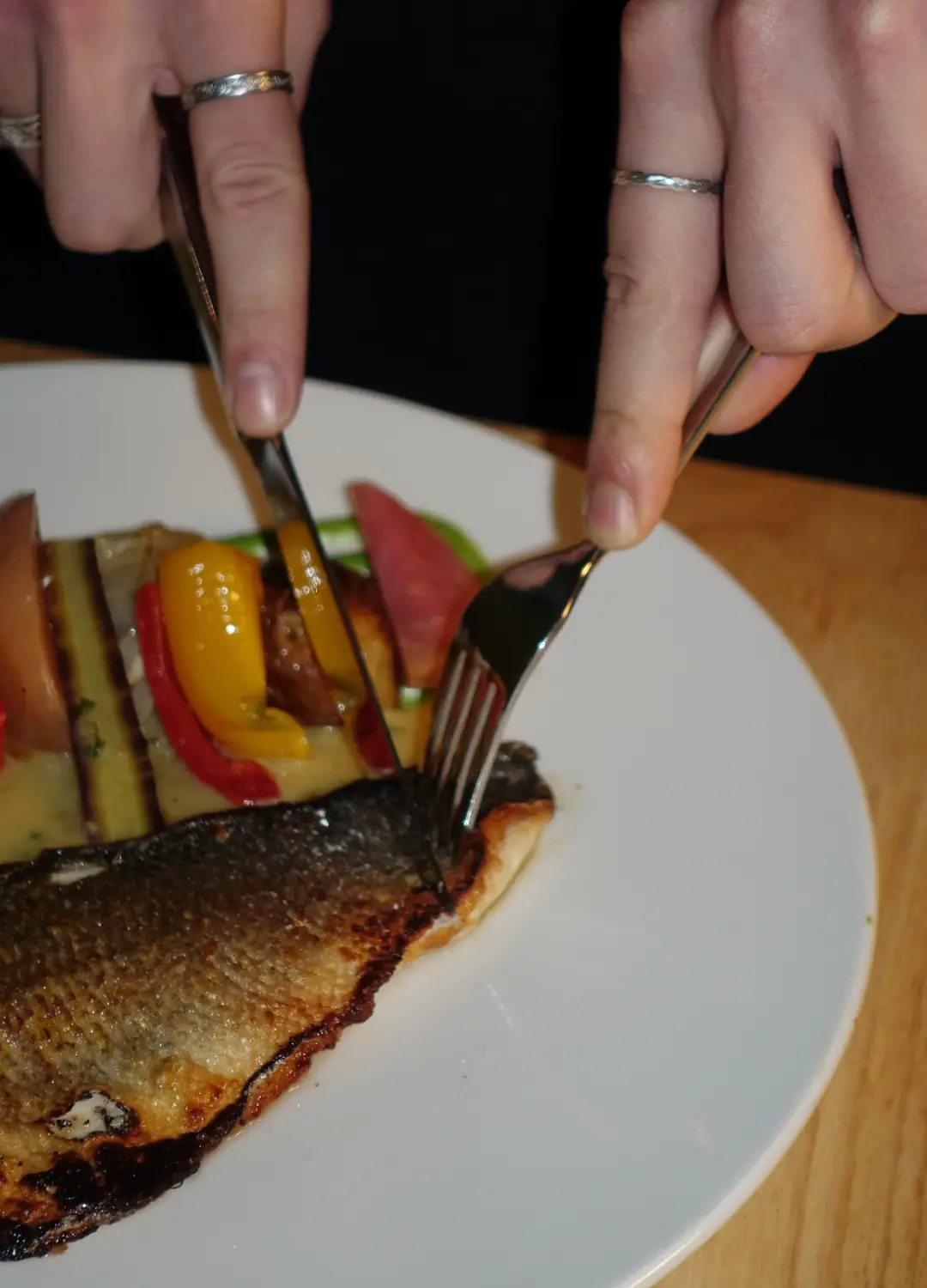 Des mains découpent une dorade rôtie