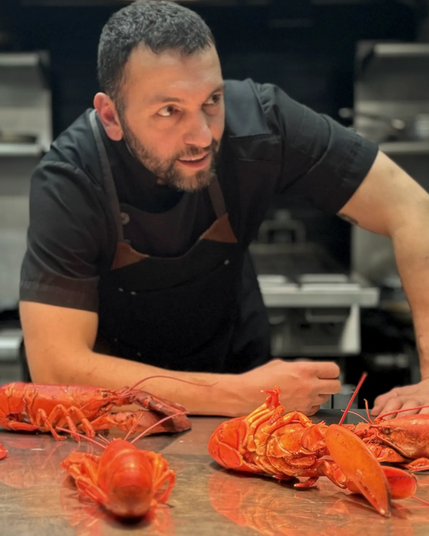 Le chef Domenico Crivello, accoudé au comptoir de la cuisine devant des homards frais
