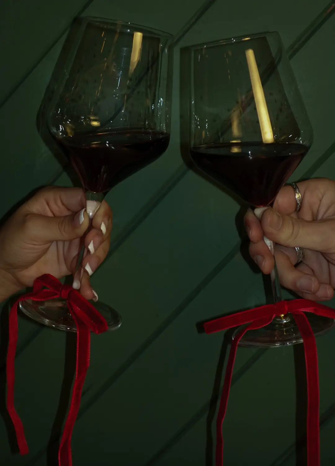 Deux verres de vin rouge qui trinquent, noués de rubans de velours rouge